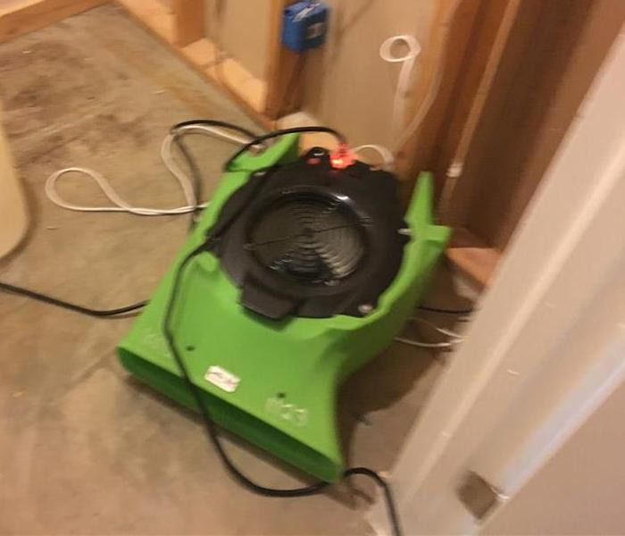 Green air movers in the process of drying a grey floor. 