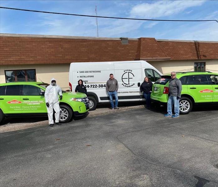 Employees posing with SERVPRO vehicles 
