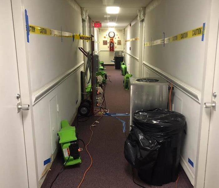Hallway in a hotel with green air movers on the floor. 