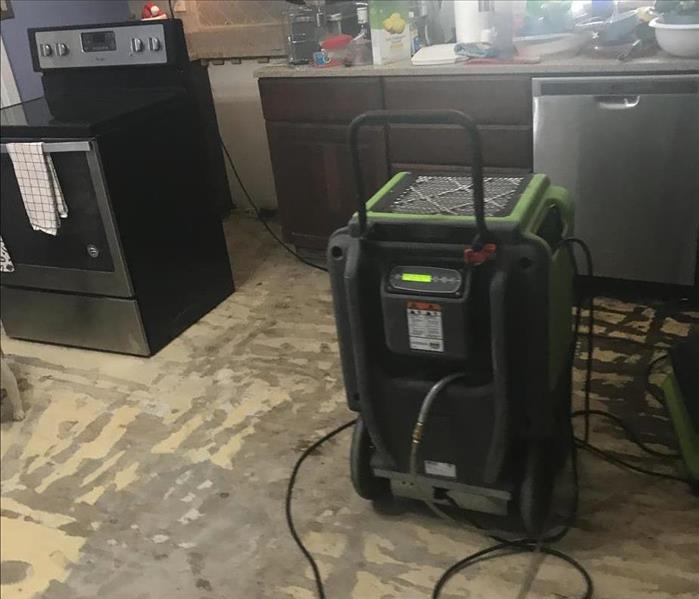 The back of a green air mover on a ripped up floor. 