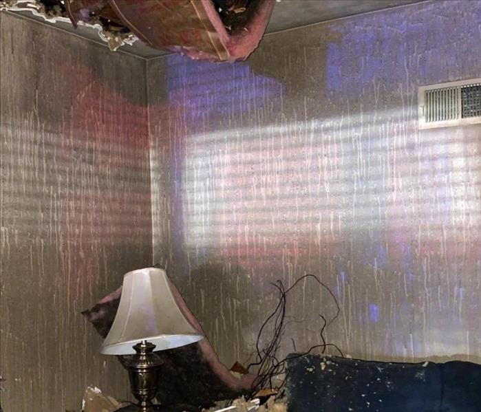 Ceiling has collapsed into a room with a couch. 