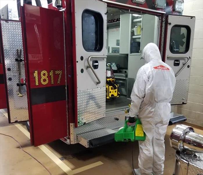 Man in PPE cleaning a fire truck. 