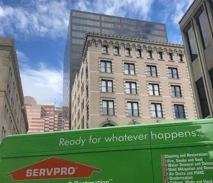 Green SERVPRO truck outside of a large building. 