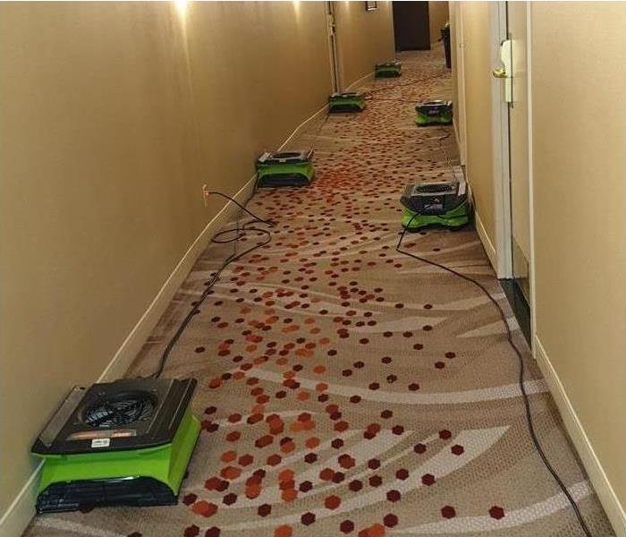 Drying equipment (air movers) placed in a hallway of a building. Concept of water restoration services